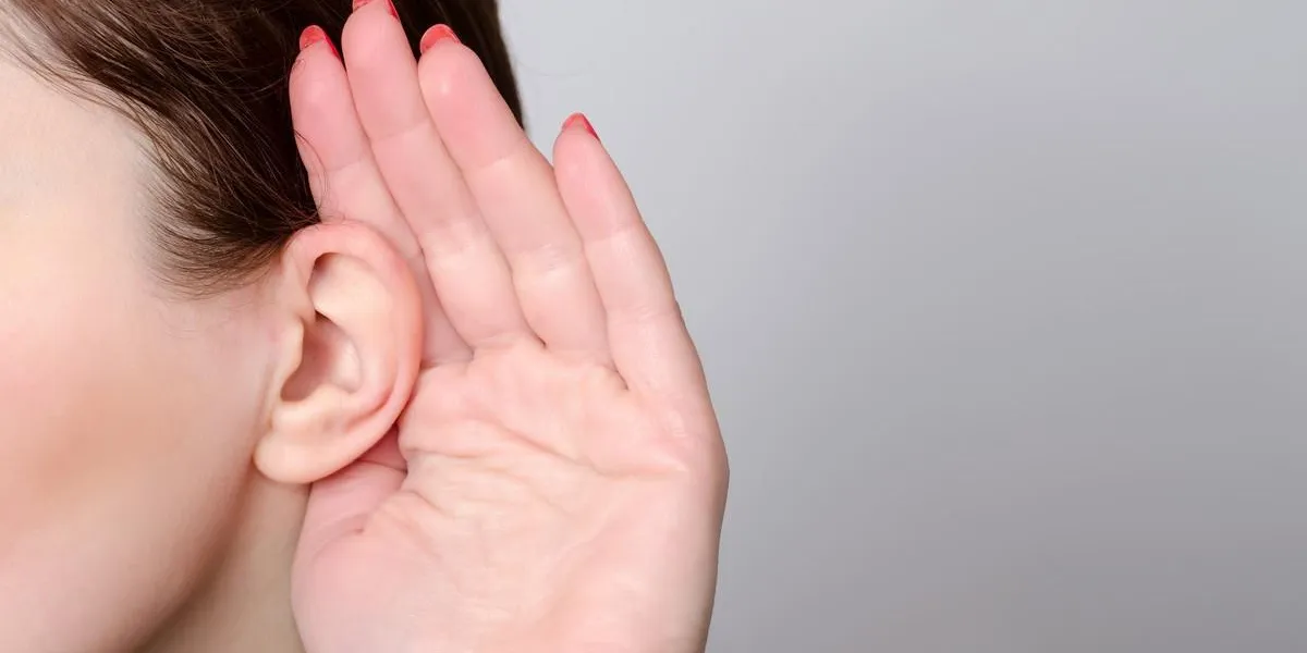 woman is listening with a hand next to her face close up woman is listening with a hand next to her face close up