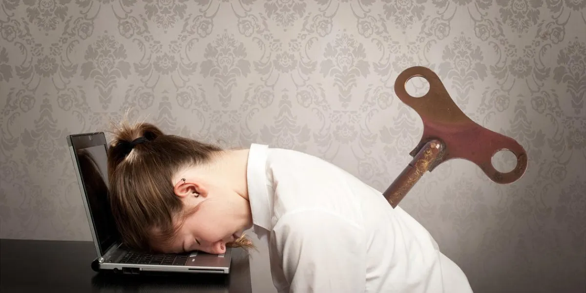 femme d'affaires avec un enrouleur de clé sur son dos, dormant sur ordinateur portable femme d'affaires avec un enrouleur de clé sur son dos, dormant sur ordinateur portable
