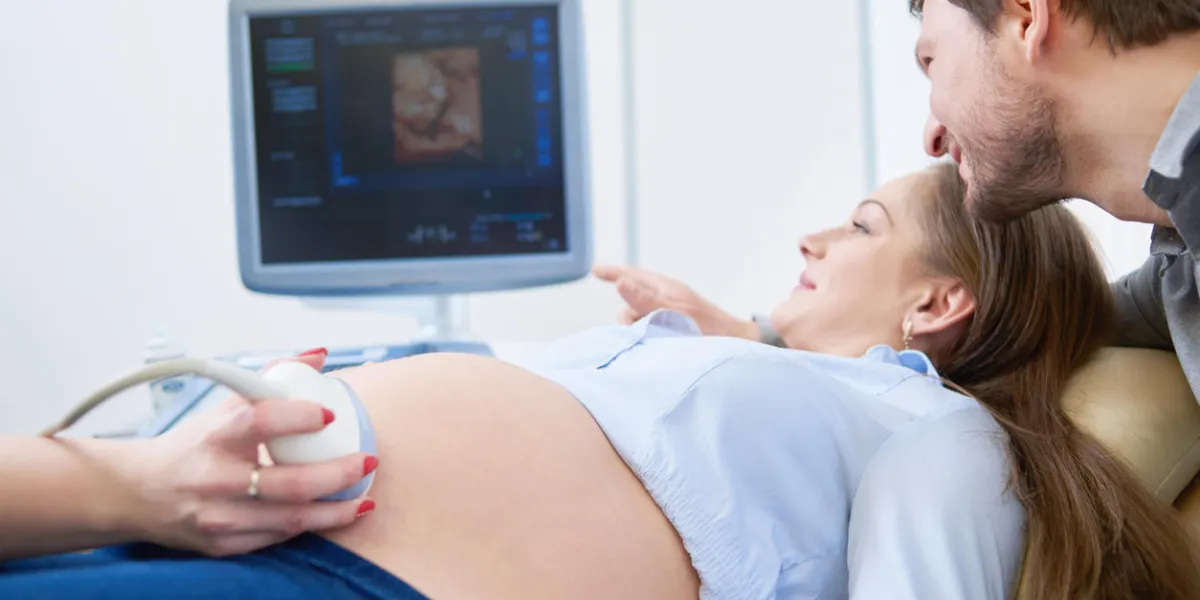 beautiful mature pregnant couple smiling looking at the sonogram results on ultrasound scanner monitor while on a checkup at the gynecologist pregnancy love family parents maternity doctor clinic beautiful mature pregnant couple smiling looking at the sonogram results on ultrasound scanner monitor while on a checkup at the gynecologist pregnancy love family parents maternity doctor clinic