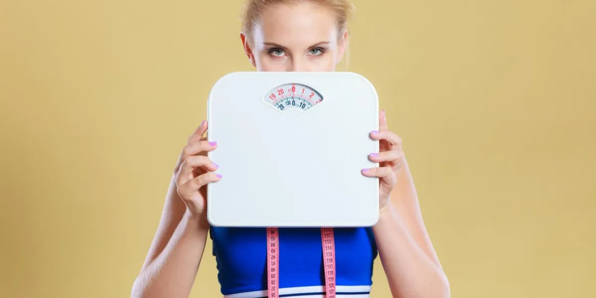 frustrated sad blonde girl covering her face with scales weight gain, time for slimming weightloss, diet