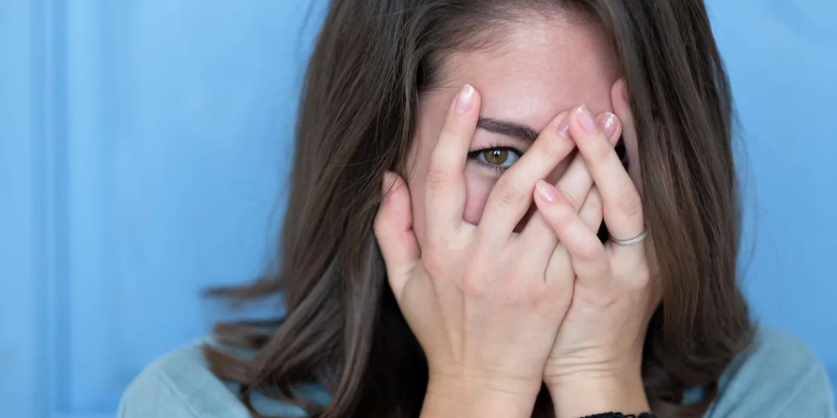 studio shot of brunette girl hiding eyes under hand while feeling ashamed caucasian young woman in white shirt covering face with hand human facial expressions and emotions studio shot of brunette girl hiding eyes under hand while feeling ashamed caucasian young woman in white shirt covering face with hand human facial expressions and emotions