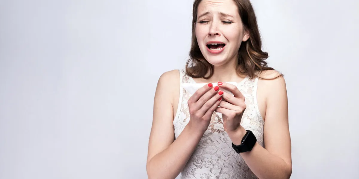 portrait of sick cold woman with freckles and white dress and smart watch on silver gray background healthcare and medicine concept portrait of sick cold woman with freckles and white dress and smart watch on silver gray background healthcare and medicine concept