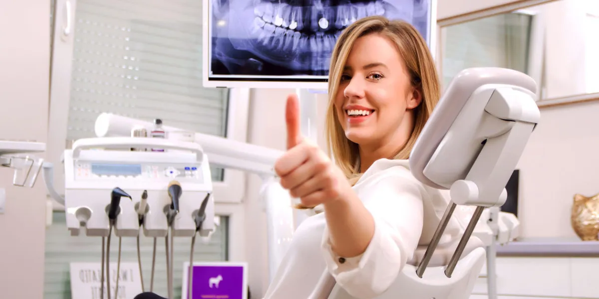 closeup portrait happy, satisfied smiling woman, female, patient in office, dental clinic giving thumbs up sign doctor visit
