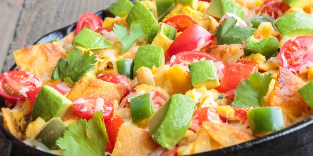 tex-mex petit-déjeuner migas à base d'œufs brouillés aux oignons, poivron rouge, jalapeno, fromage, garni de tomates cerises, d'avocat et de coriandre