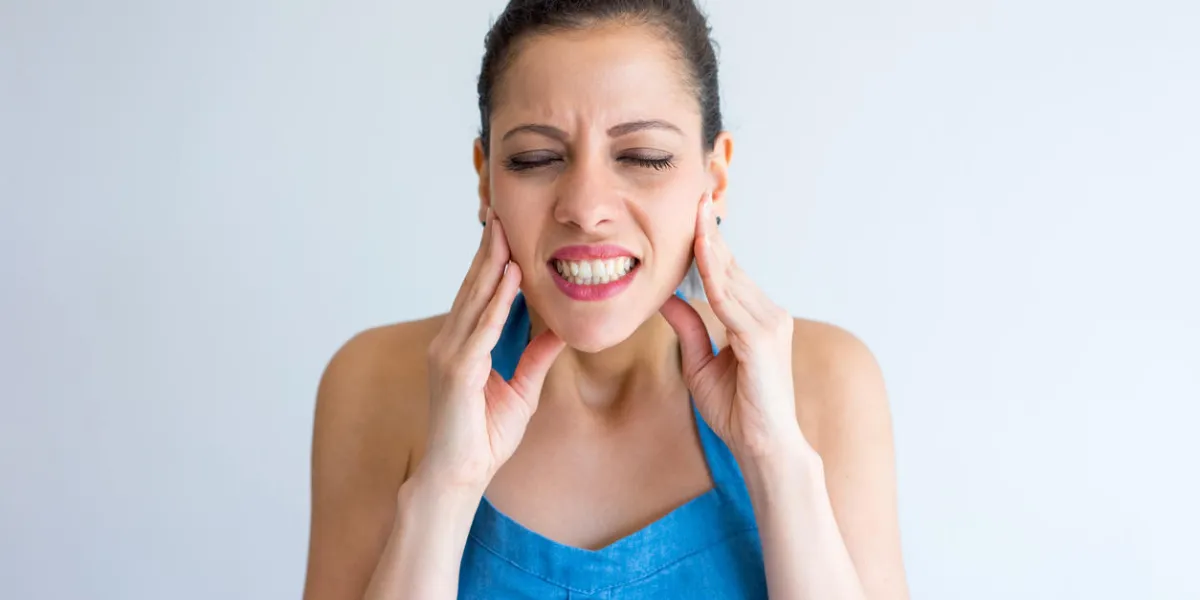 annoyed young woman suffering from toothache and touching jaw irritated girl with closed eyes gritting teeth from pain hurt concept annoyed young woman suffering from toothache and touching jaw irritated girl with closed eyes gritting teeth from pain hurt concept