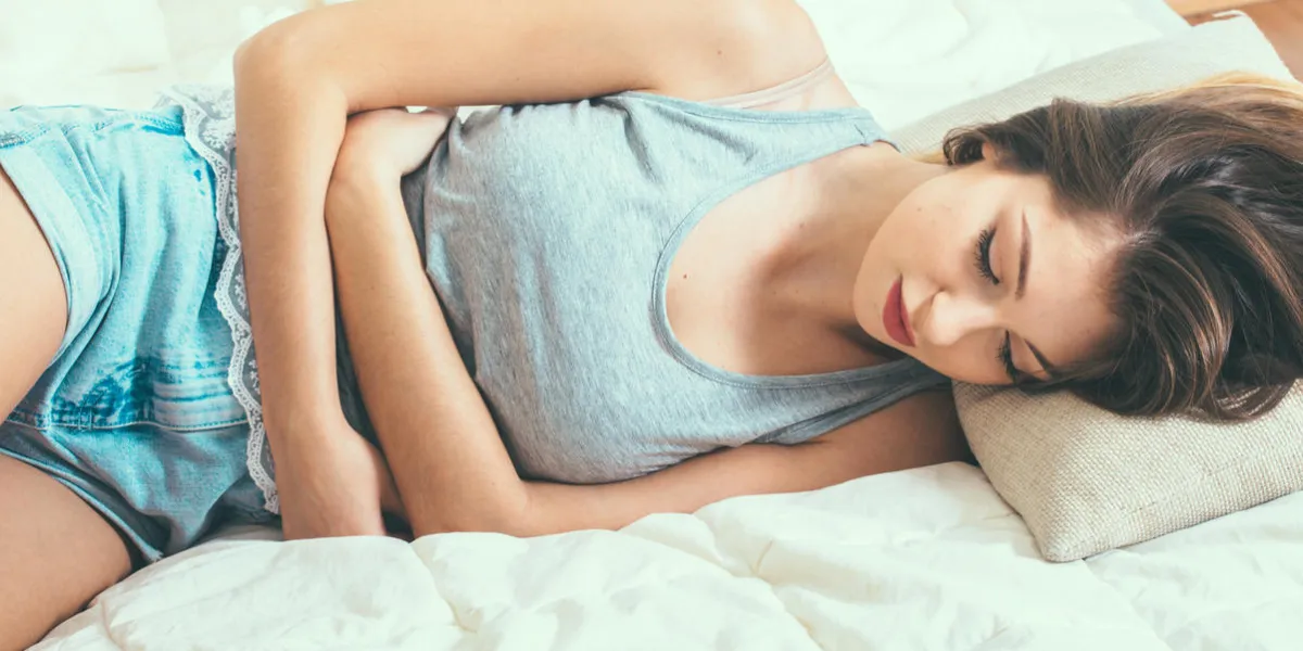 woman stomach pain on bed top view indor shot