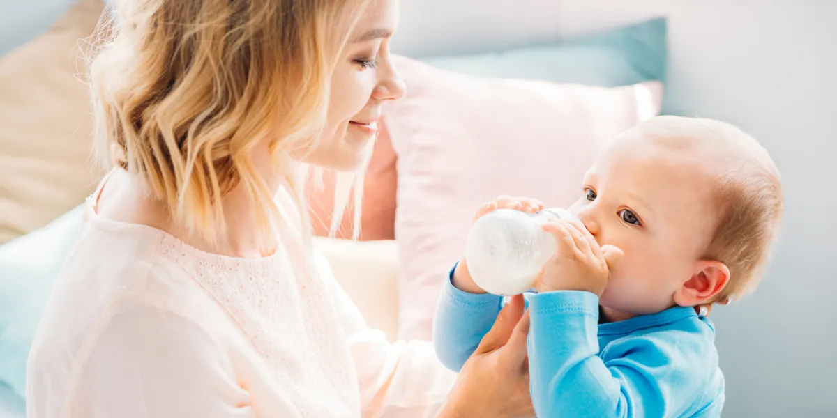 happy mother feeding her little child with baby bottle at home happy mother feeding her little child with baby bottle at home
