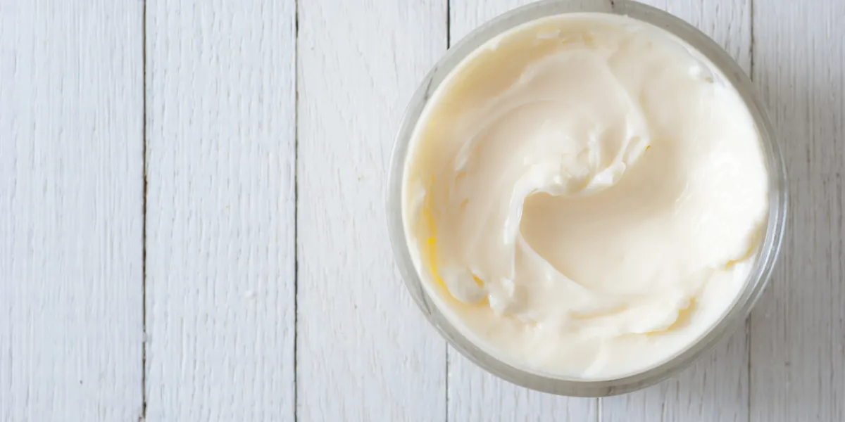 cosmetic cream with herbal flower on white wooden table