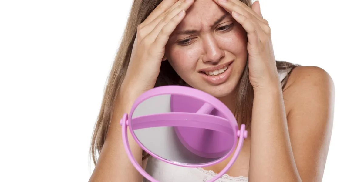 malheureuse jeune fille en regardant son bouton sur son visage