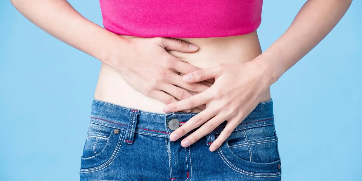 woman feel bad and touch her belly on the blue background
