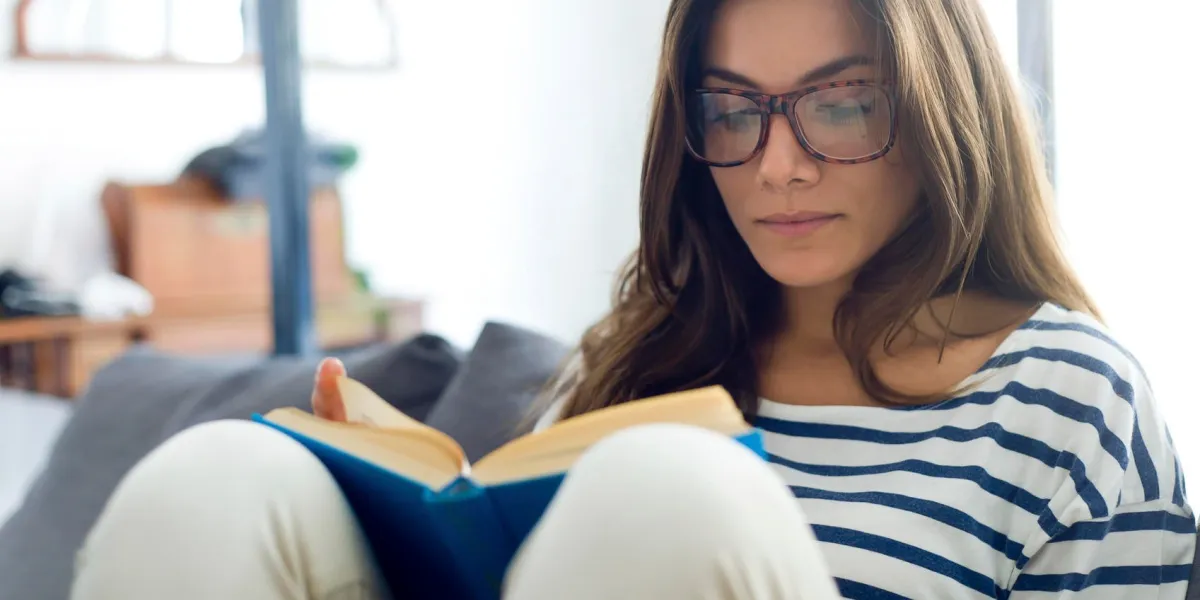 portrait de la belle jeune femme lisant un livre sur le canapé