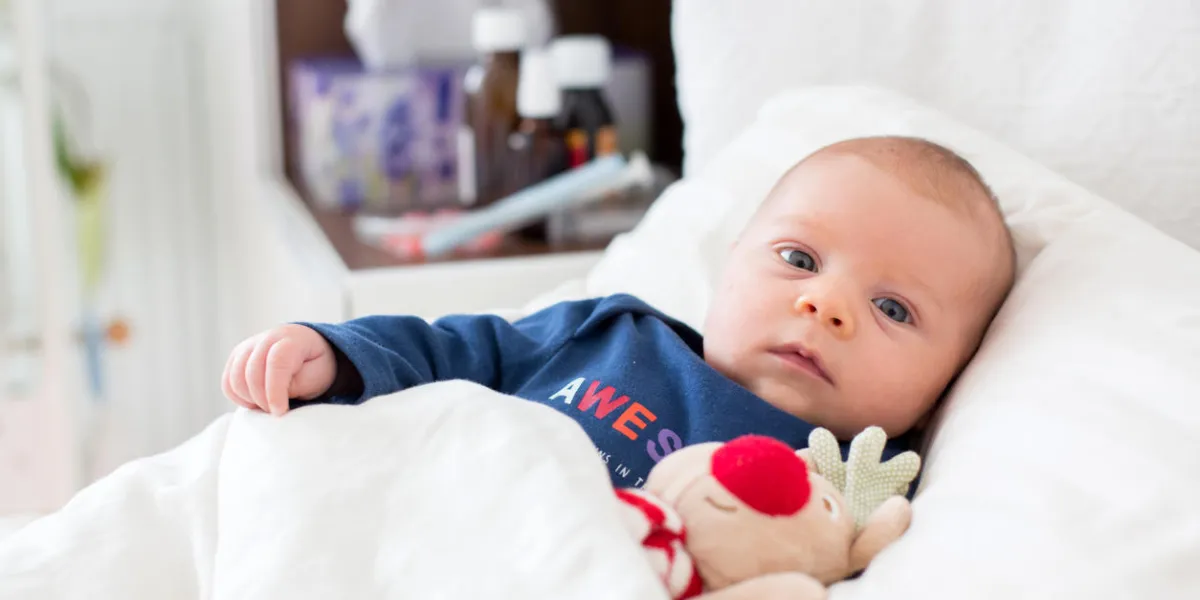 cute newborn baby boy, lying in bed with cold and fever cute newborn baby boy, lying in bed with cold and fever