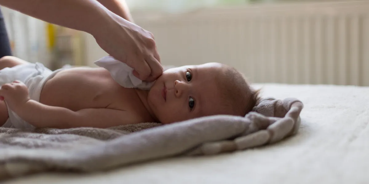 caucasian two months old baby boy lying on the bed wraped in a blanket