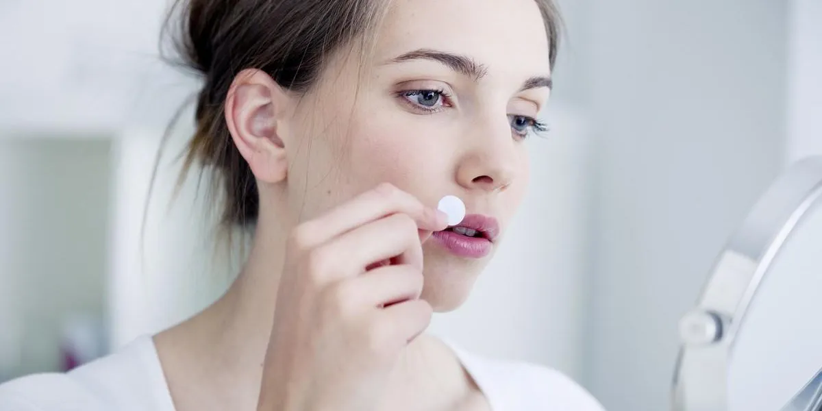 femme s'appliquant un patch contre l'herpès labial femme s'appliquant un patch contre l'herpès labial