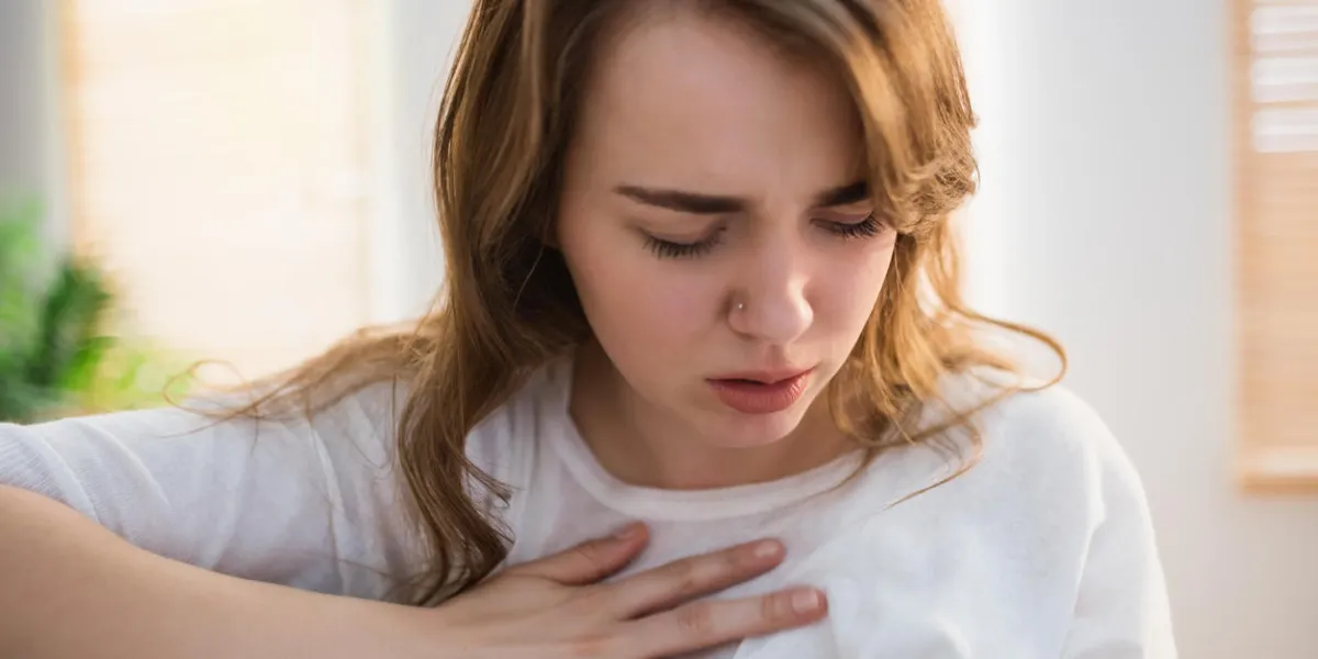 pretty woman suffering from chest pain on couch