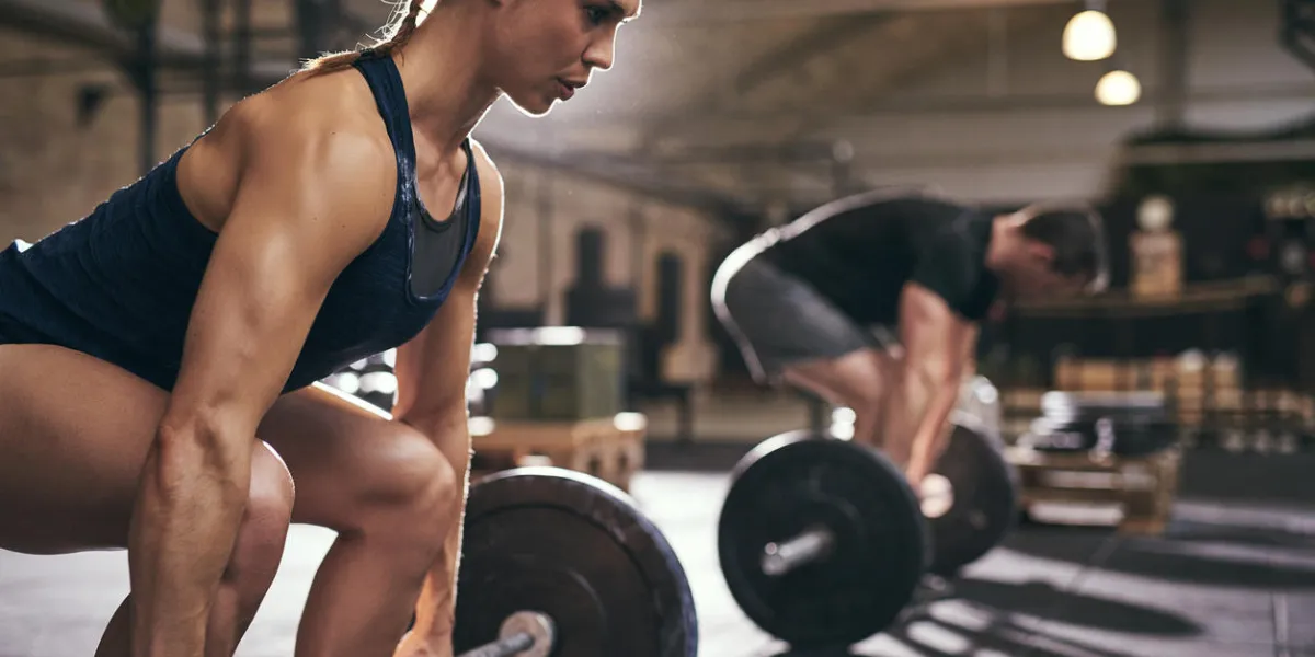 fit people preparing to deadlift and holding barbells horizontal indoors shot