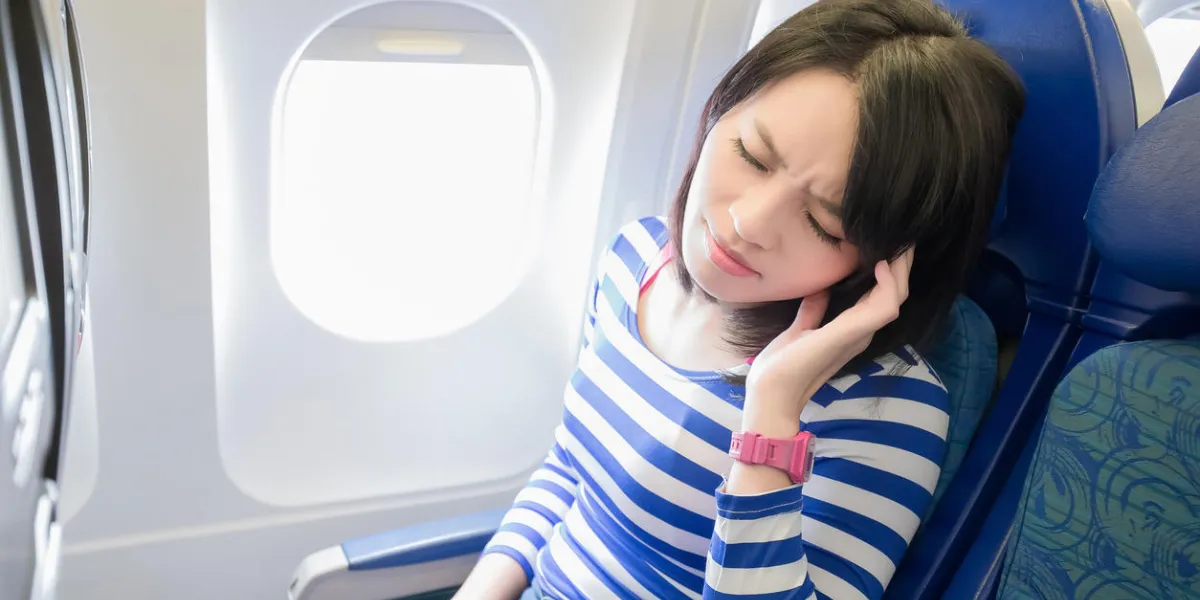 happy young woman is sitting in the airplane, feel headache, asian