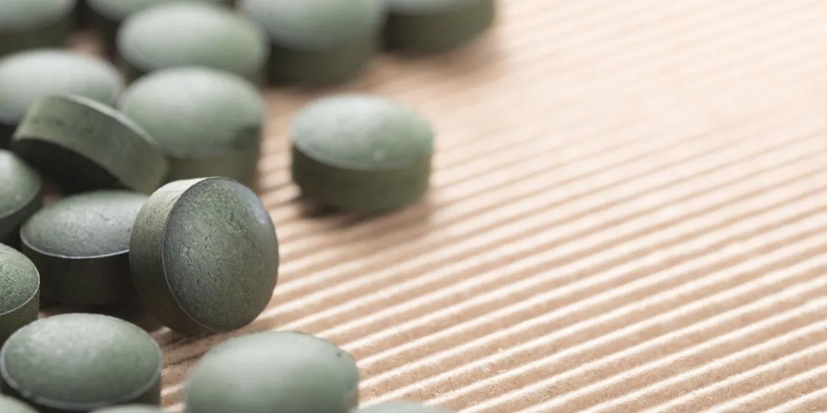 detail of many organic spirulina tablets with low depth of field over cardboard background detail of many organic spirulina tablets with low depth of field over cardboard background