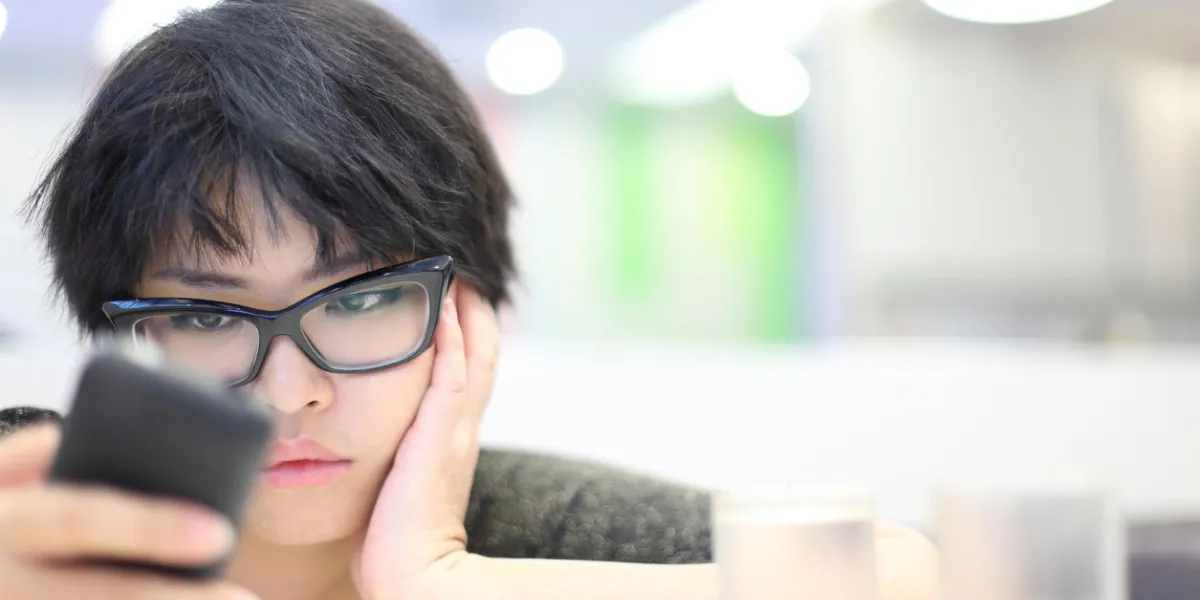 fille cheveux courts à la recherche de téléphone portable et se sentir malheureux