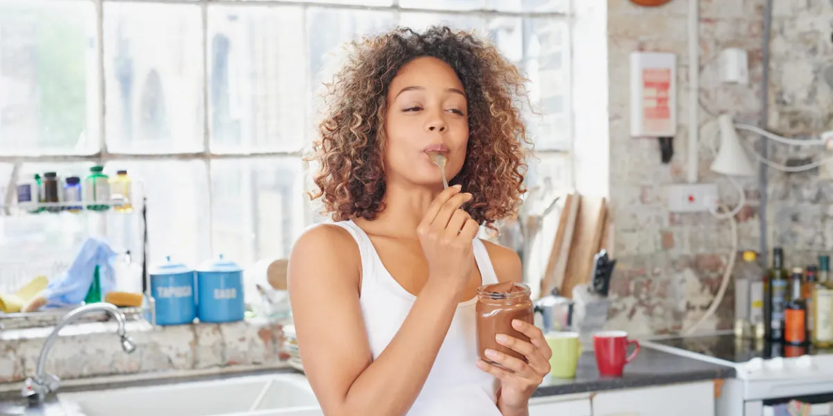 fille de race mélangée se livrant à un visage effronté manger du chocolat à tartiner du pot à l'aide d'une cuillère savourer chaque bouchée fille de race mélangée se livrant à un visage effronté manger du chocolat à tartiner du pot à l'aide d'une cuillère savourer chaque bouchée