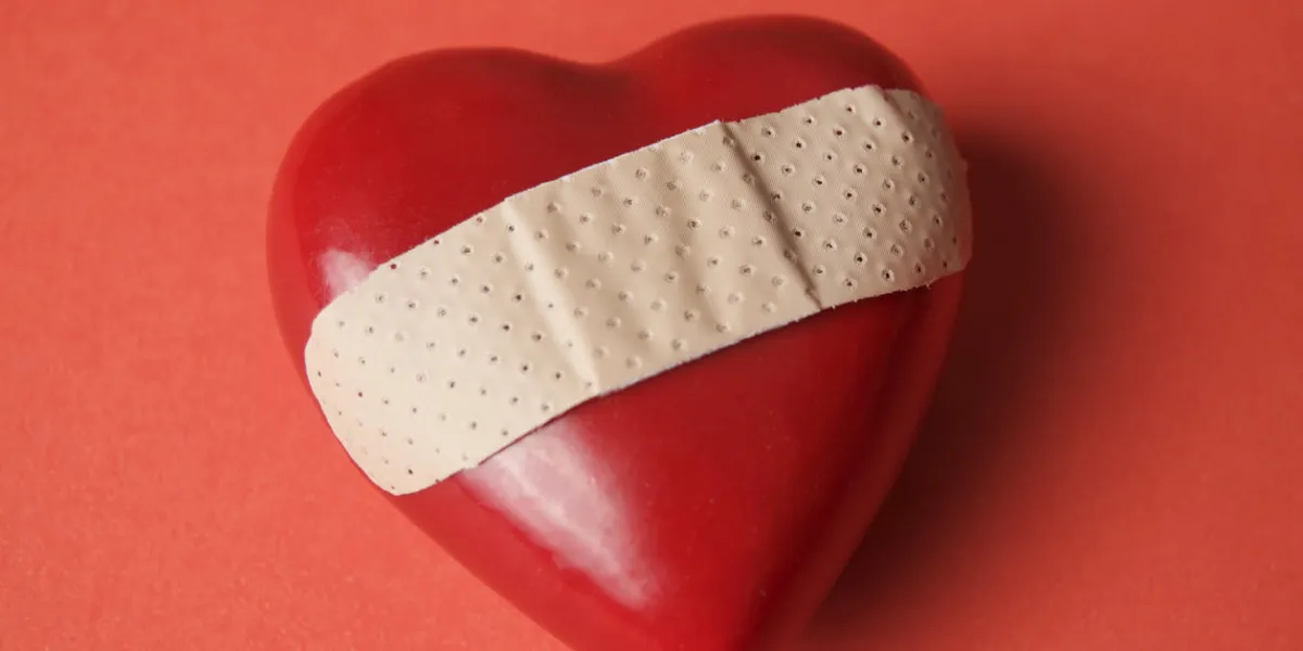 red heart on red background with a band-aid across it red heart on red background with a band-aid across it