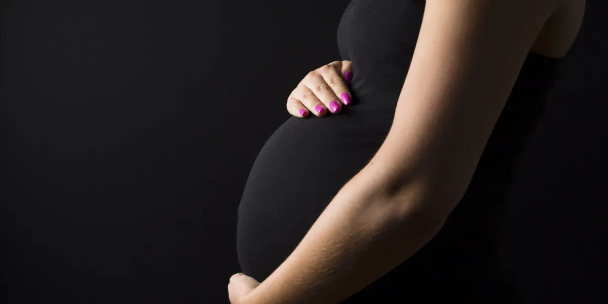 side view of a beautiful pregnant woman body with her hands on her tummy on black background side view of a beautiful pregnant woman body with her hands on her tummy on black background