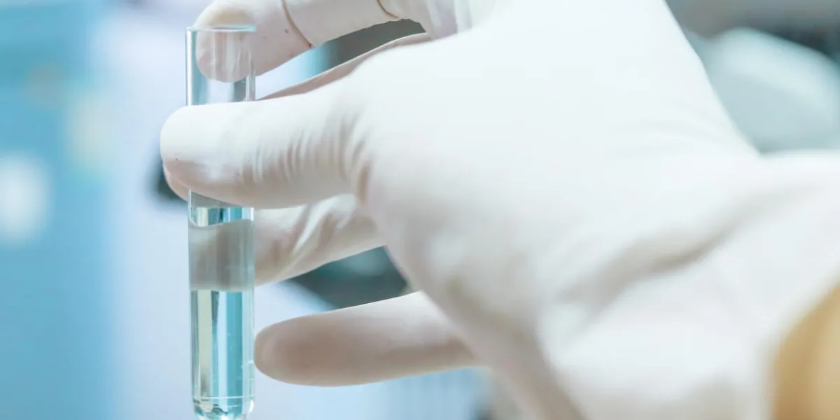 close-up of glass tube with blue fluid in scientist hand during medical test