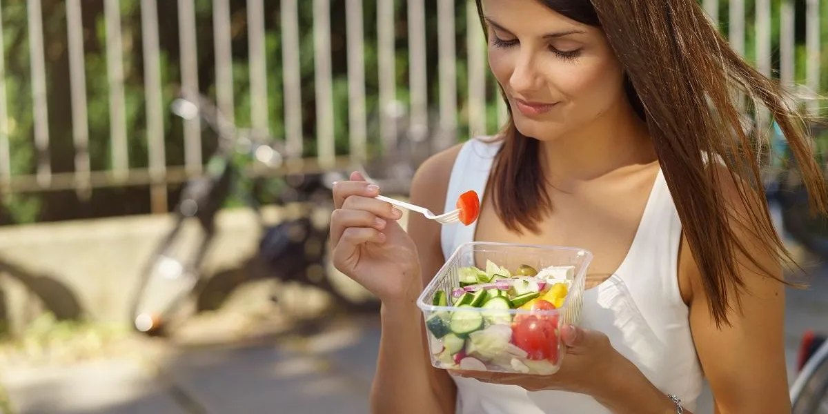 junge frau ist in der stadt unterwegs und isst einen salat