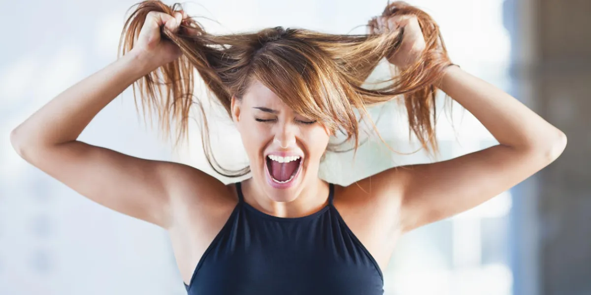 frustrated young woman screaming and pulling her hair