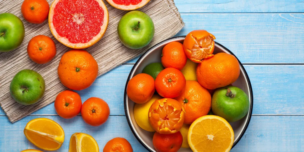 fond de saine alimentation sur une table en bois bleue dans un bol - pamplemousse, oranges, mandarines et pommes vue de dessus avec espace copie fond de saine alimentation sur une table en bois bleue dans un bol - pamplemousse, oranges, mandarines et pommes vue de dessus avec espace copie