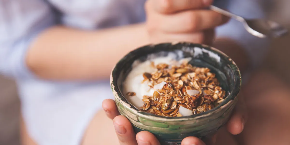 young woman with muesli bowl girl eating breakfast cereals with nuts, pumpkin seeds, oats and yogurt in bowl girl holding homemade granola healthy snack or breakfst in the morning