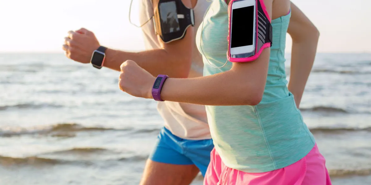 couple en cours d'exécution sur la plage avec leurs lecteurs mp3