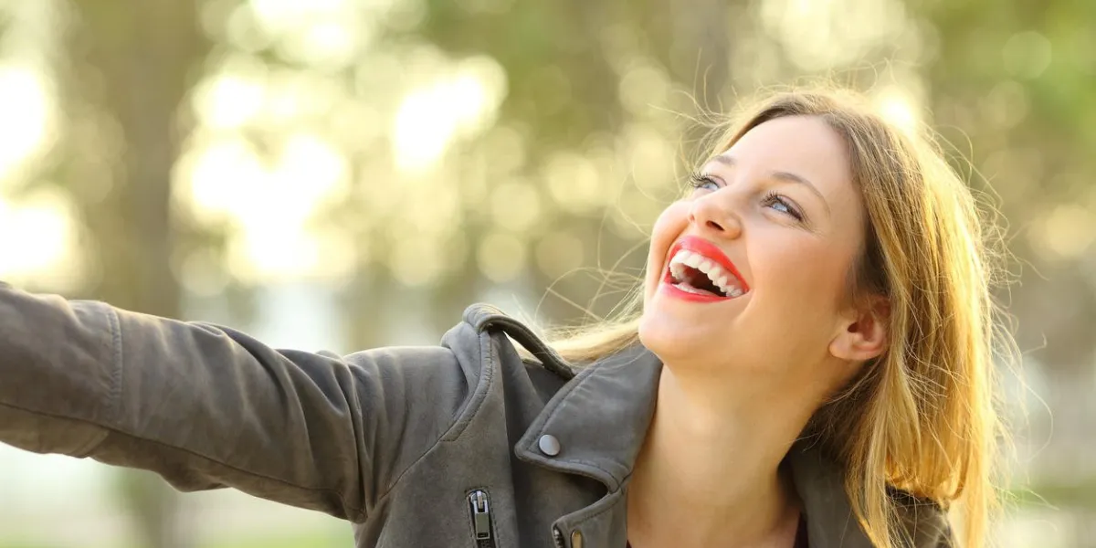 portrait of a candid girl laughing and joking outdoors in a park