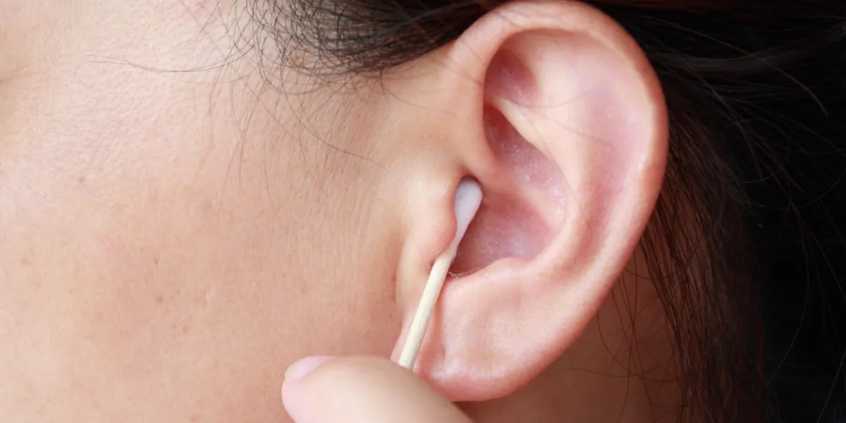woman holding cotton swab and cleaning ear woman holding cotton swab and cleaning ear