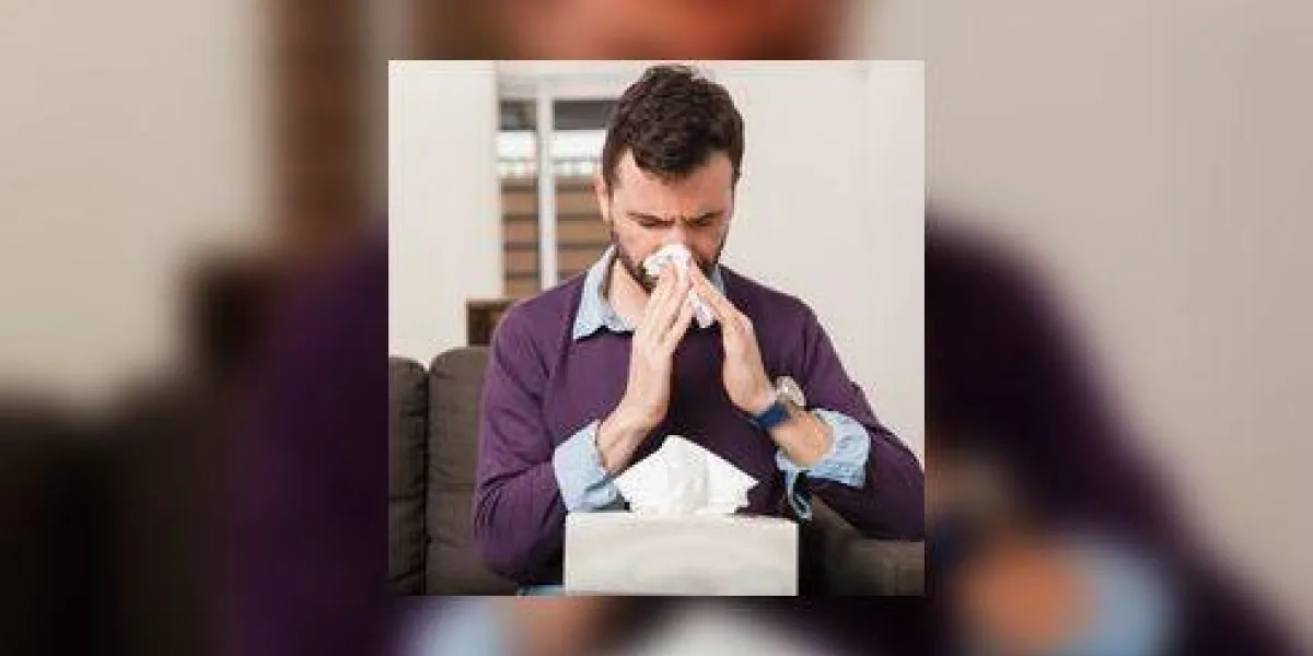 homme avec une barbe se moucher avec une boîte de mouchoirs et se battre un rhume à la maison