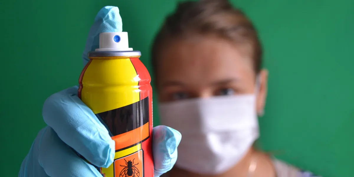 aerosol for insect control in the hands of a woman wearing a mask