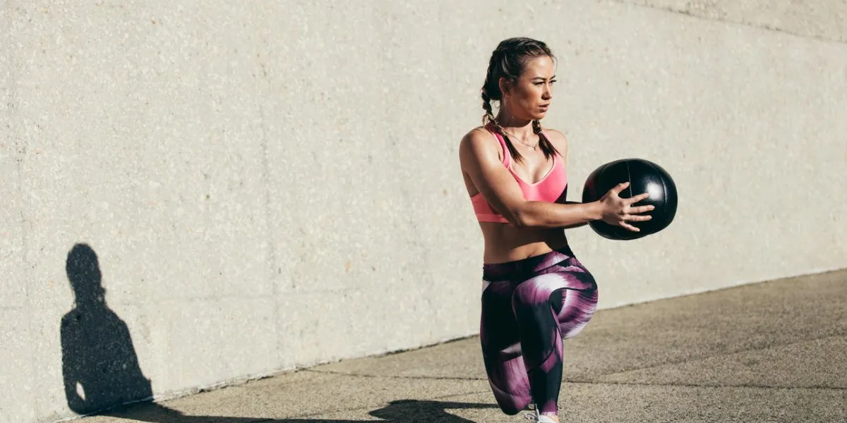 sportswoman doing stretching exercise with medicine ball muscular woman exercising fitness ball outdoors sportswoman doing stretching exercise with medicine ball muscular woman exercising fitness ball outdoors