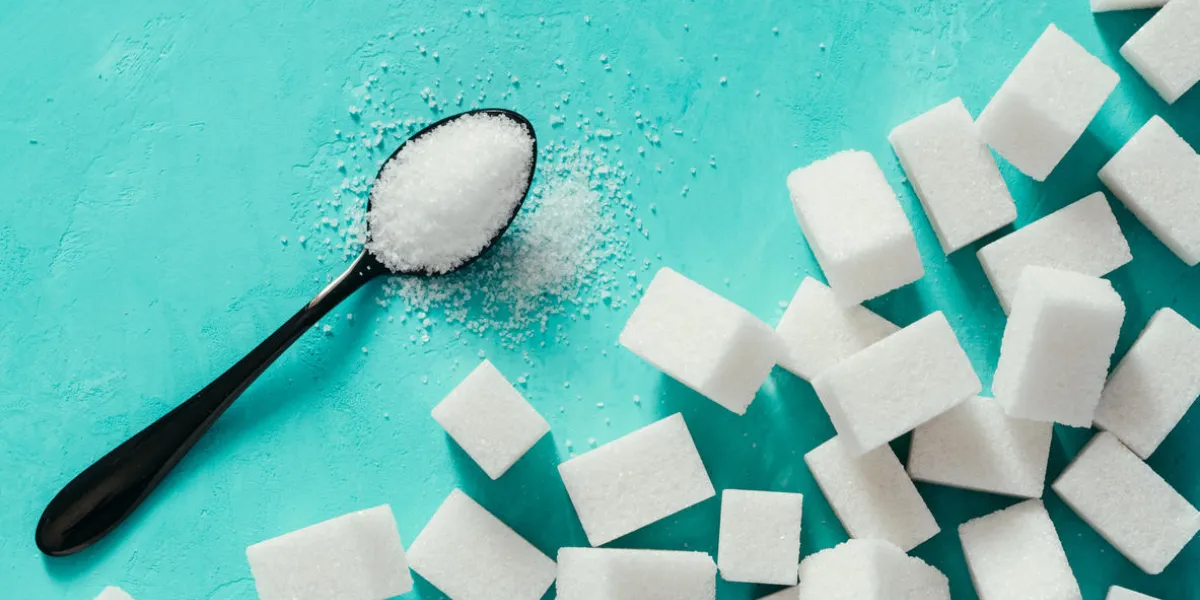 background of sugar cubes and sugar in spoon white sugar on turquoise background sugar with copy space top view or flat lay