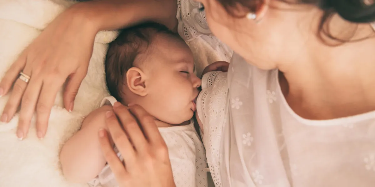 beautiful young mom holding her 3 months baby mather nursing baby family at home