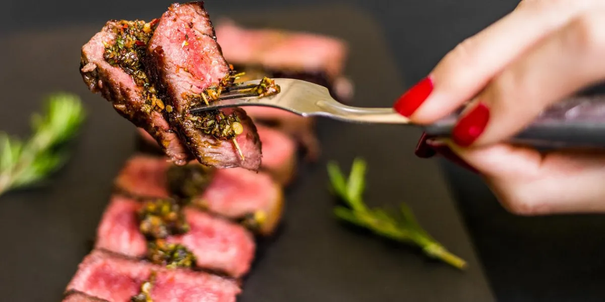 young woman eating new york strip porterhouse steak meat