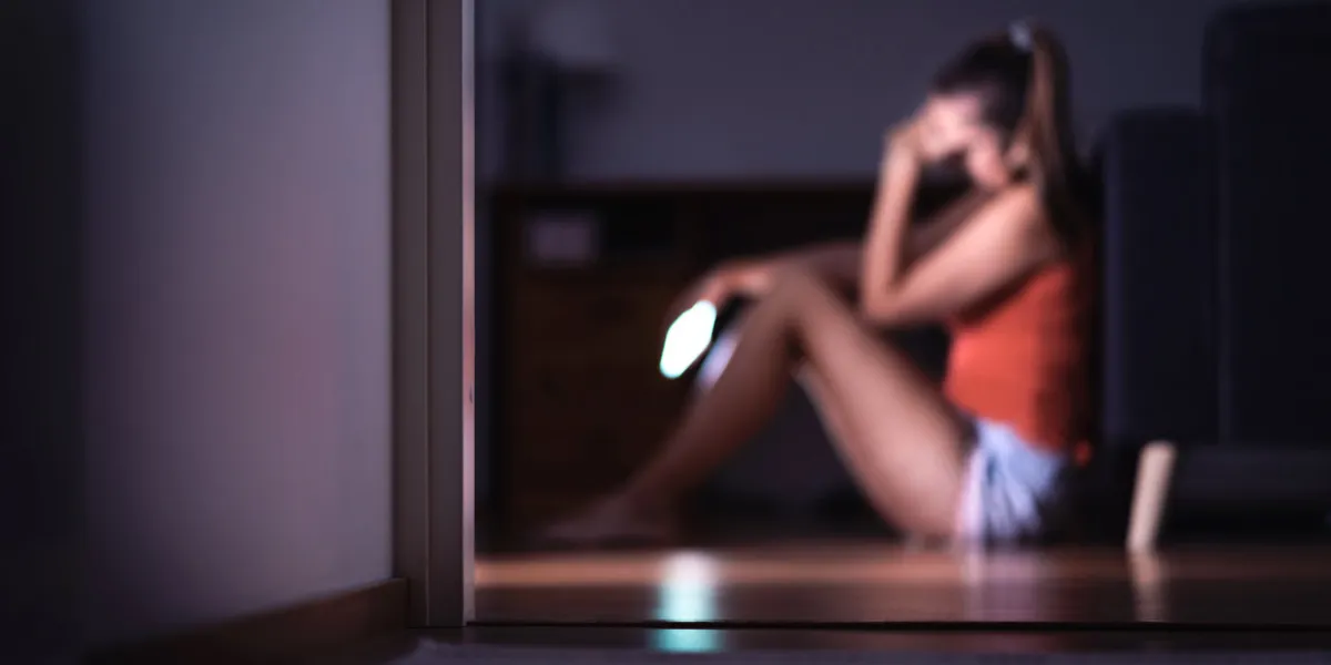 sad teenager with smartphone in her room sitting on floor lonely teen girl crying with mobile phone harassment or online cyber bullying in social media or internet mean message or troll comment sad teenager with smartphone in her room sitting on floor lonely teen girl crying with mobile phone harassment or online cyber bullying in social media or internet mean message or troll comment