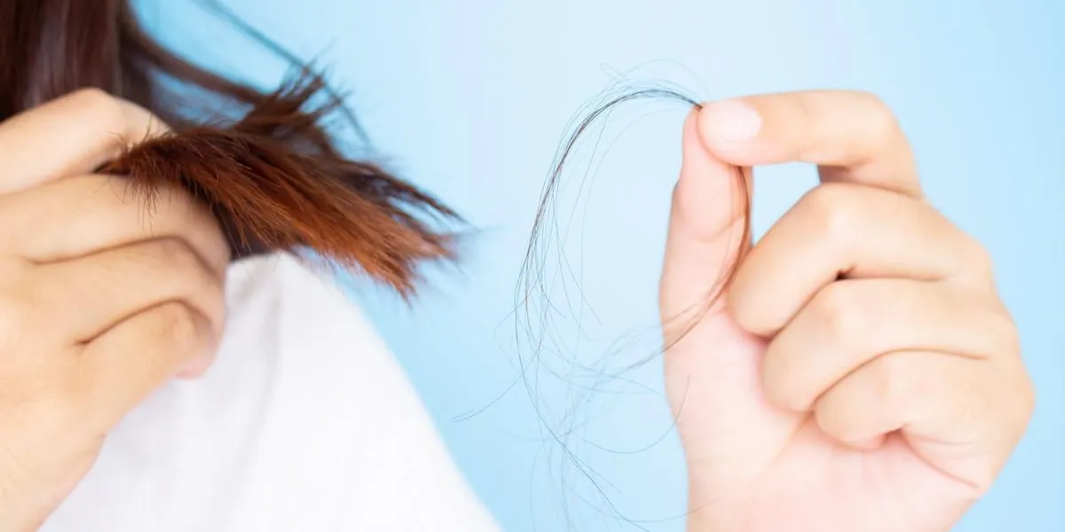 woman's hand holding hair falling from her head in white t-shirt with blue background young asian female age between 25-35 years old