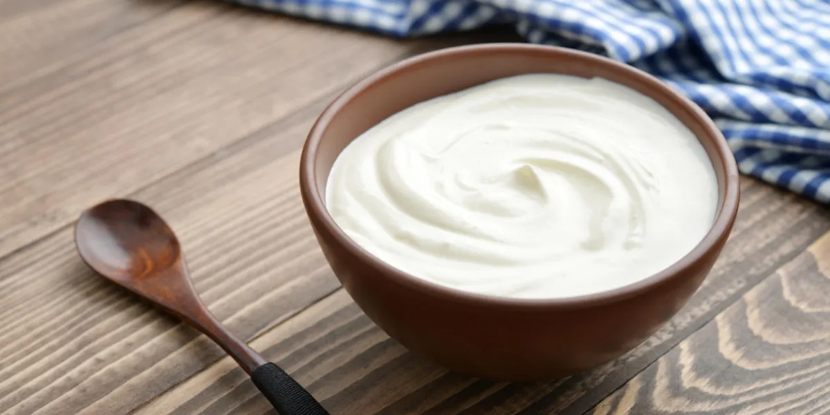yogurt in bowl with spoon on wooden background