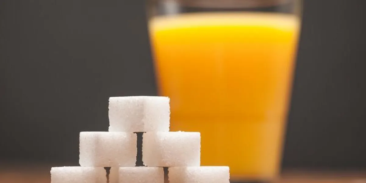 amounts of sugar in food - glass of orange juice, on wooden table and dark background, selective focus amounts of sugar in food - glass of orange juice, on wooden table and dark background, selective focus