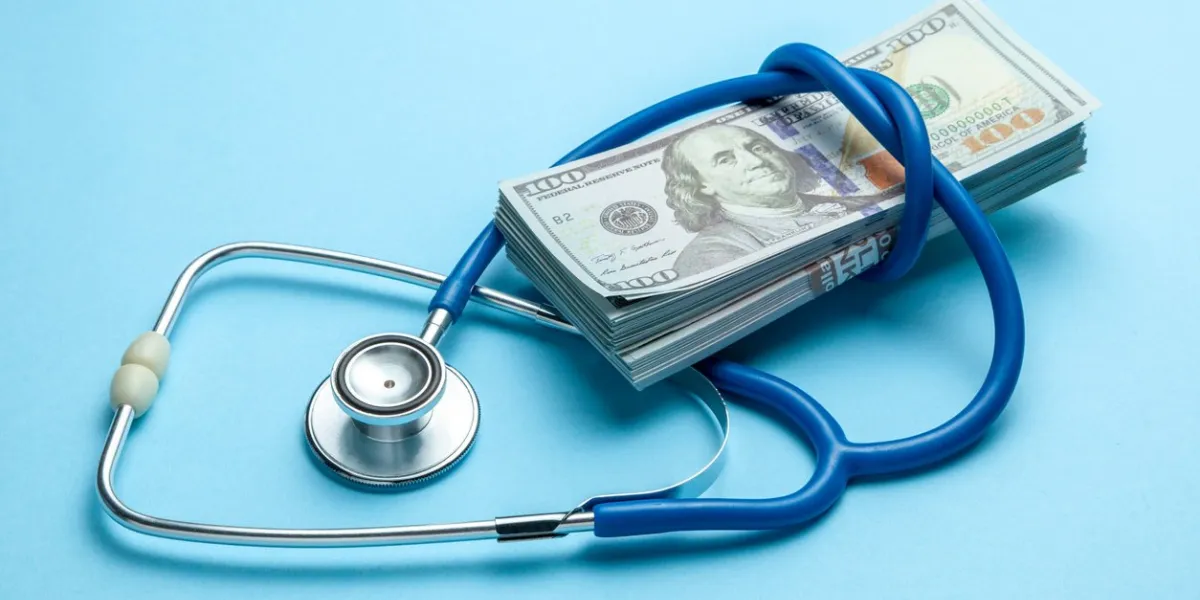 stack of cash dollars and stethoscope on blue background the concept of medical strechevka or expensive medicine, doctors salary