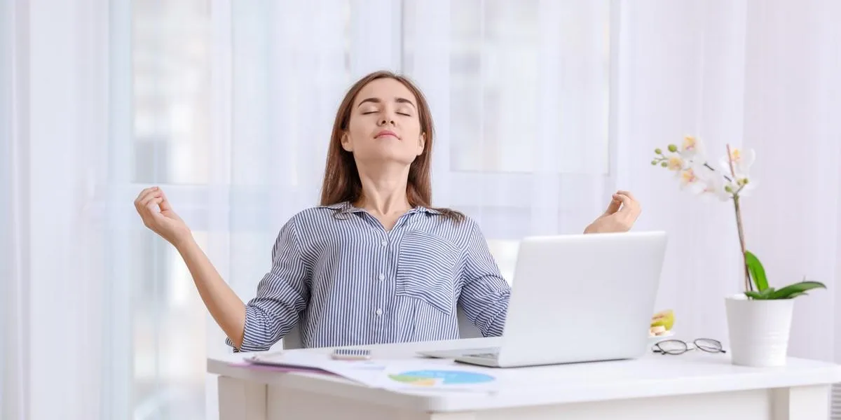 young woman meditating while working at table in office