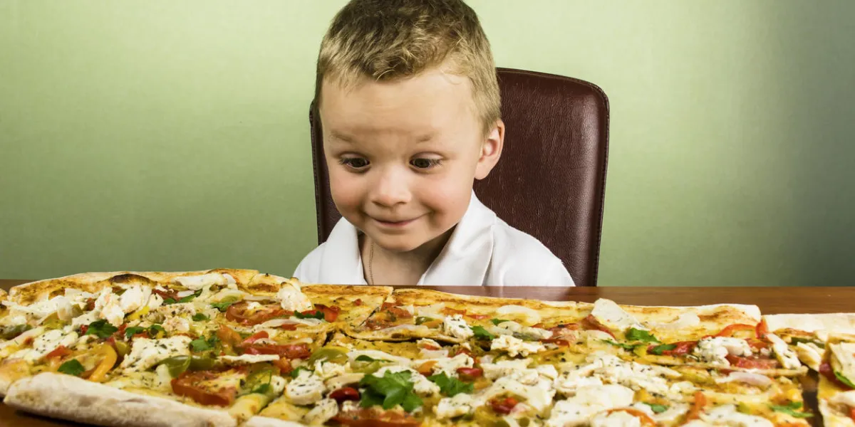 boy looks at a large pizza on the table