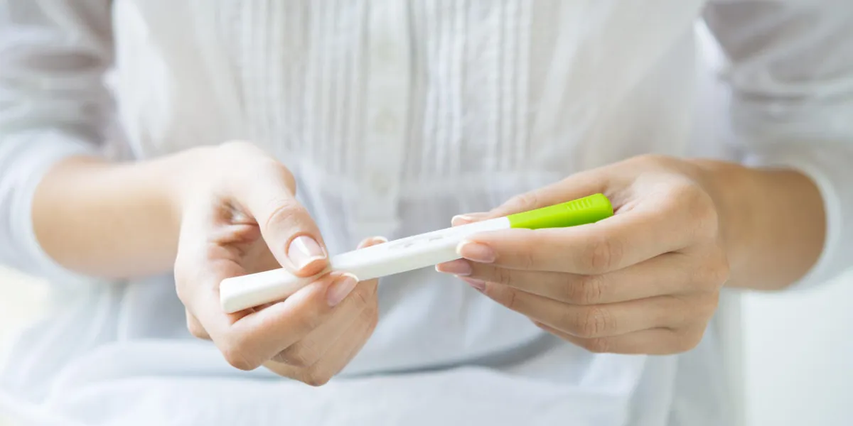 closeup shot of a woman looking at pregnancy test she's is checking her pregnancy exam detail hands of a girl holding pregnancy test shallow depth of field with focus on pregnancy test