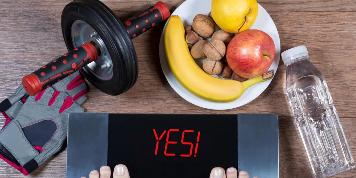 female feet on digital scales with word yes surrounded by sport accessories (ab roller wheel, fitness gloves), plate with healthy food and water bottle concept of active healthy lifestyle top view female feet on digital scales with word yes surrounded by sport accessories (ab roller wheel, fitness gloves), plate with healthy food and water bottle concept of active healthy lifestyle top view