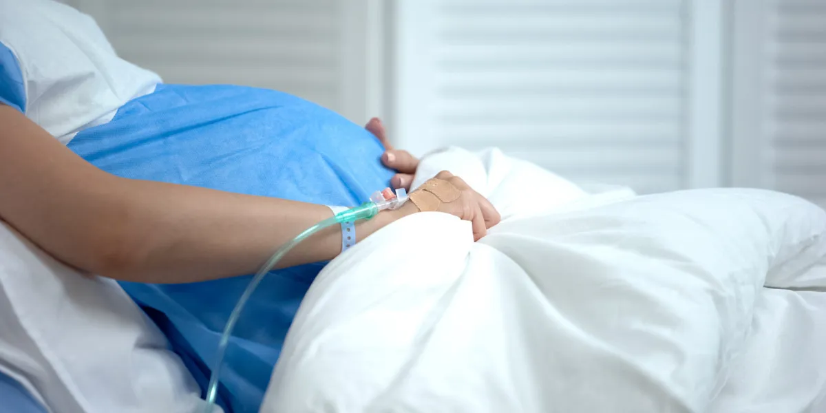 pregnant woman holding blanket, feeling abdominal pain, risk of miscarriage